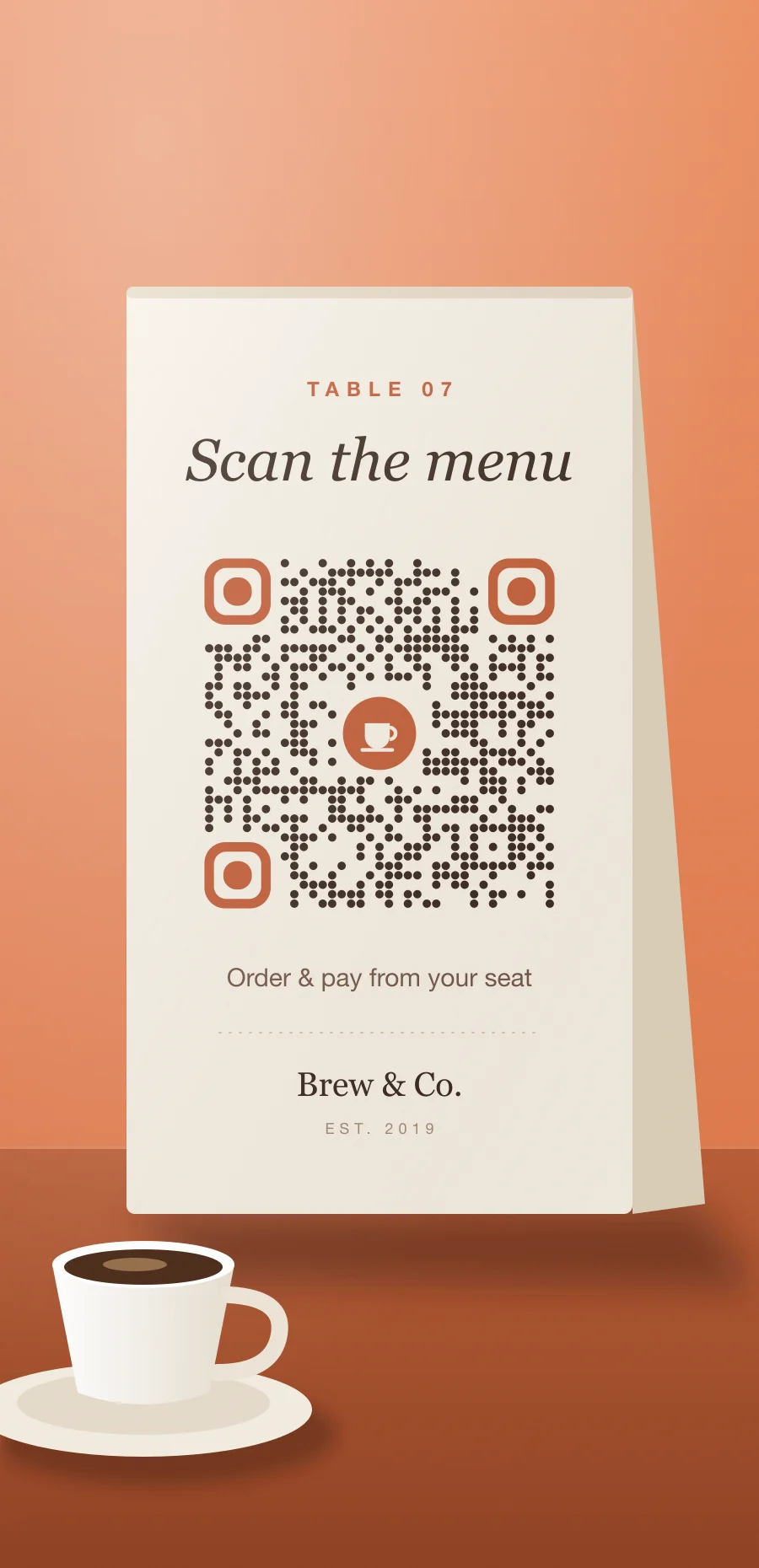 Cream café table tent with a dotted brown QR code under the words “Scan the menu”, next to a cup of coffee