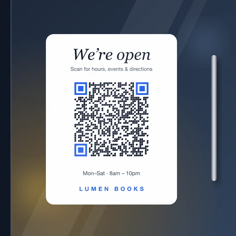 White “We’re open” decal on a glass shop door with a blue-eyed QR code for hours and directions